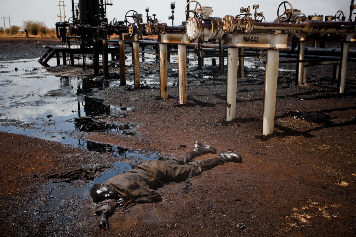 Sudan, Heglig, 2012.  A Sudan Armed Forces (SAF) soldier lies dead covered in oil next to a leaking oil facility after heavy fighting between southern Sudanese SPLA troops, after they entered the north Sudan oil town of Heglig mid April. Dominic Nahr