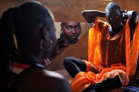 Bineta Ndiaye, 22, looks at herself in the mirror as her friend Coumba Faye, 19, fixes her hair in Faye’s house in the village of Ndande. Every year, inhabitants of the village take part in a Sufi Muslim ceremony called Gamou-Ndande. The ceremony combines nights of praying and chanting as well as traditionally animist ceremonies. (Joe Penney/Reuters)