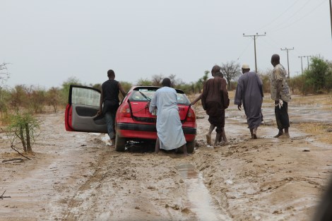 Chibok guys pushing a car out of the mud on a rainy morning. 