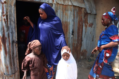 Falmata Gana, widowed after members of the Islamist sect Boko Haram killed her husband in 2012, walks out of the small room she shares with 11 children. Maiduguri, northeastern Nigeria. Photo by Chika Oduah. December 17, 2014