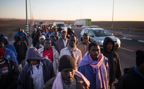 BEER SHEVA, ISRAEL - DECEMBER 16: (ISRAEL OUT) African migrants walk on a highway as they try to walk to Jerusalem in protest after abandoning a detention facility in the southern Israeli desert on December 16, 2013 near Beer Sheva, Israel. Over 100 African migrants abandoned the 'open' Israeli detention center, which opened last week, to march to Jerusalem to protest a law allowing authorities to keep them in open-ended detention until the resolution of their asylum requests are granted or they are deported or volunteered to leave the country. (Photo by Uriel Sinai/Getty Images)