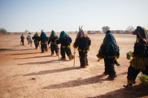 Fibre masks wearers from Tcheriba village march towards the Regional Stadium of Dedougou. Photo by Jacob Balzani Loov