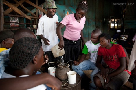 A group of Kenyans drink busaa, a traditional fermented beer, from a common pot using long straws - in a crowded busaa club at midday in a Nairobi slum on March 27, 2013. Busaa is made by crudely fermenting maize, millet, sorghum or molasses. At Kshs 35 per liter it is much cheaper than a Kshs120 half-liter bottle of commercial beer. The local brew was legalised in 2010 and since then busaa clubs have become increasingly popular. Drinking is on the rise in Kenya, especially among young people. Photo: Benedicte Desrus