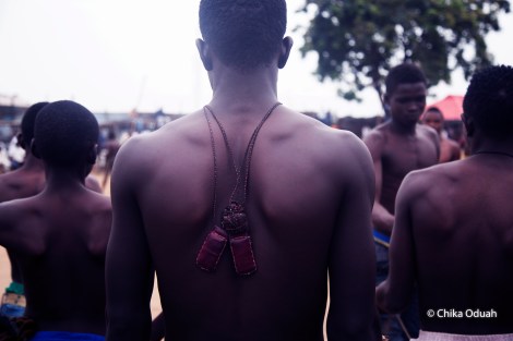 A boxer wears a leather pouch of charms around his neck. The fighters are usually decorated in amulets- strands of animal hairs wrapped around gemstones, verses of the Koran written on scraps of paper, other mystical things stuffed into leather pouches. Photo by Chika Oduah. March 2016