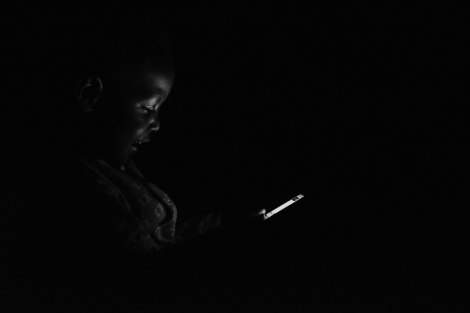 A 1-year-old boy uses a mobile phone during a blackout. Uganda