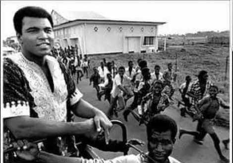 A swarm of Nigerian boys run after Muhammad Ali. Lagos, 1964 
