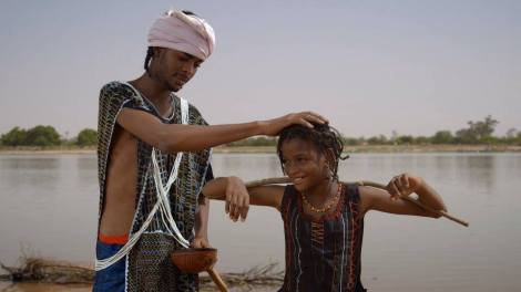 A man playfully pats the head of a Fulani child. A scene from the film. 